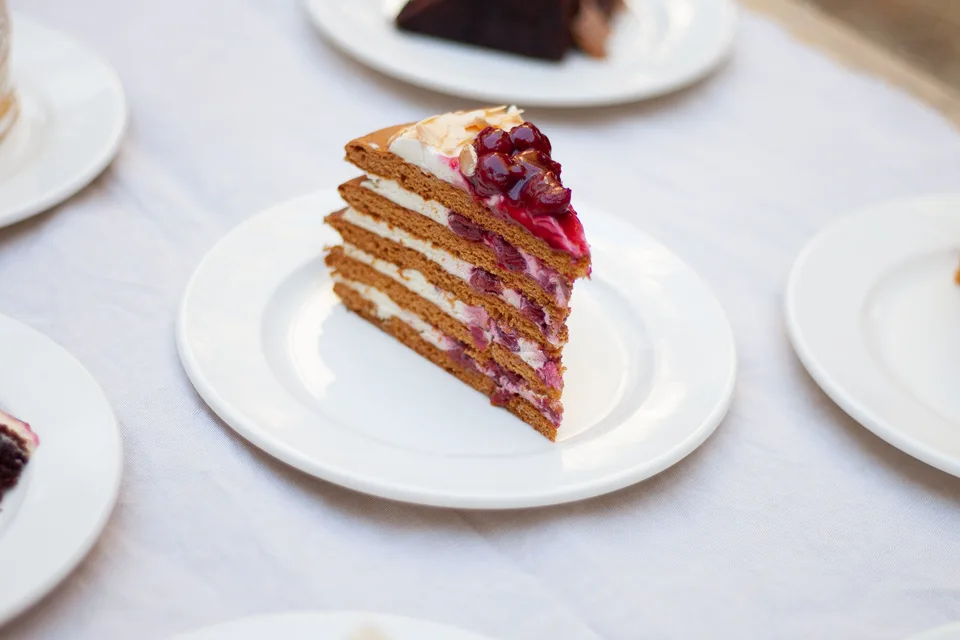 BookNoFees: Fotografie ilustrativă: Felie de tort în straturi, cu fructe de pădure, pe o farfurie albă