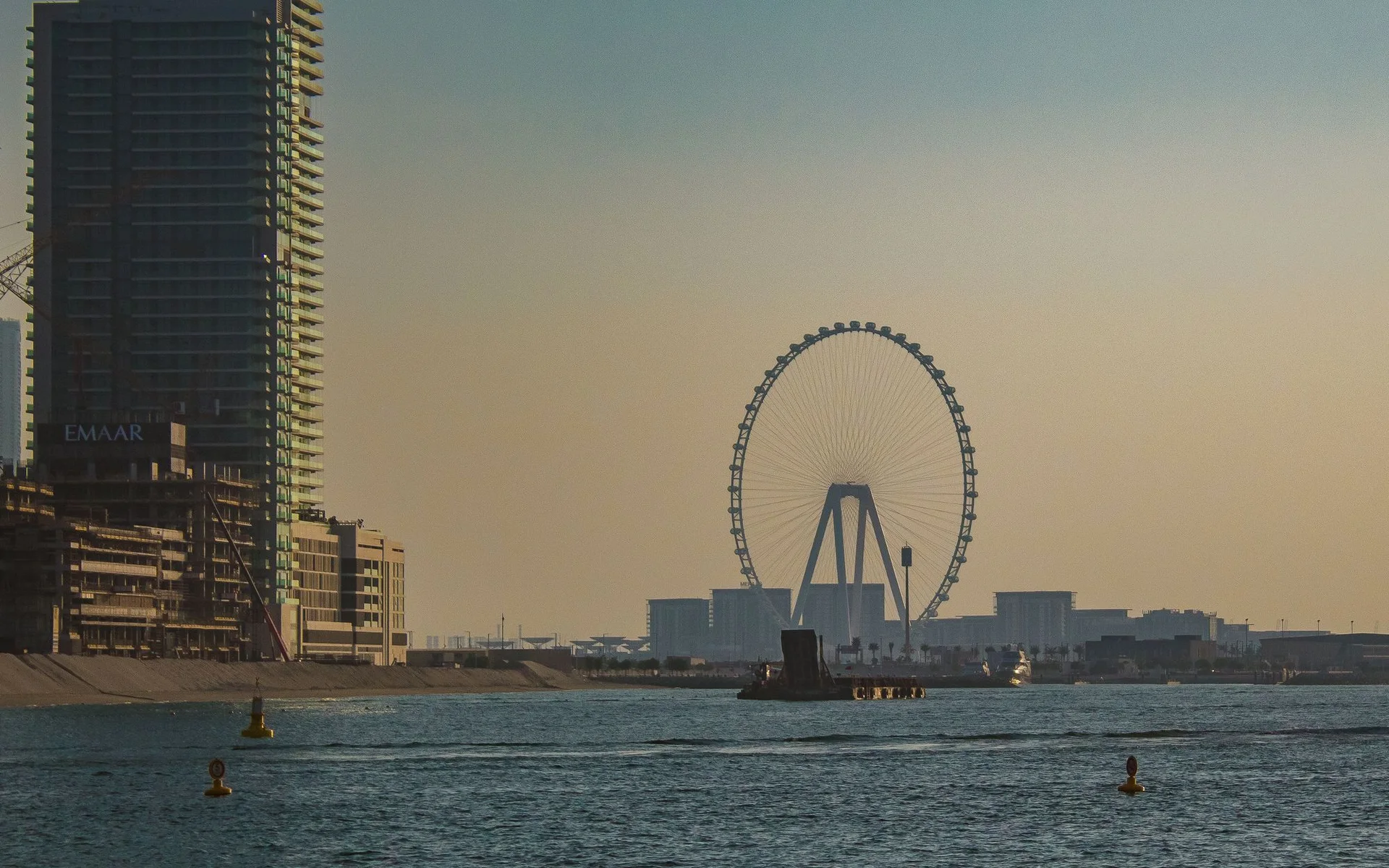 Orizontul orașului Dubai cu roata gigantică la apusul soarelui