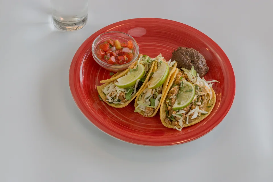 BookNoFees: Fotografie ilustrativă: Trei tacos cu felii de lime și salsa pe o farfurie roșie